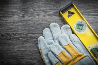 Yellow construction level protective gloves on wooden board