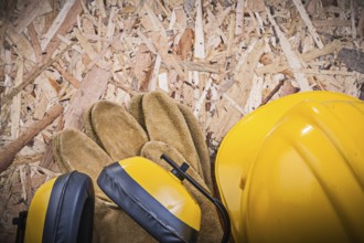 Safety leather gloves building helmet earmuffs on chipboard