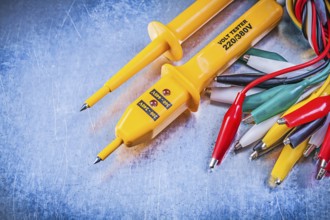 Yellow electrical tester set of multicolored crocodile clip cables on metallic background