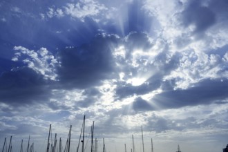 Cloudy sunset beam sky with marina sailboat masts on bottom
