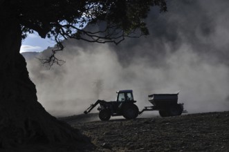 Tractor spreading lime with a fertiliser spreader, West Coast, New Zealand, Oceania