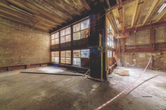 Interior of an abandoned building with wooden floor, rubble and light coming in through high