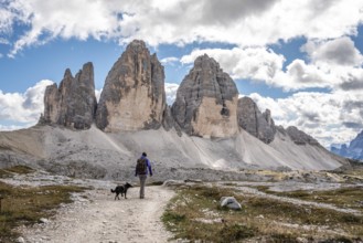 A female person hiking lonely with her dog around the Drei Zinnen mountains, the Dolomites in South