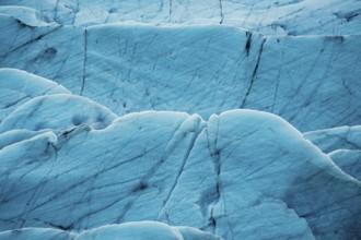 Detailed close-up of a glacier's textured surface with deep blue tones, iceberg, glacier, snow, ice