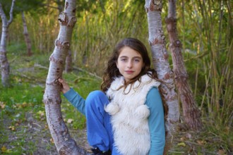 Autumn kid girl relaxed in forest with green canes background