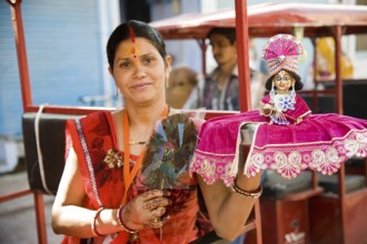 Woman holding krishna idol on hand, mathura, uttar pradesh, india, asia