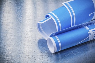 Blue rolled blueprints on scratched metallic background construction concept