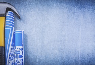 Blue rolled blueprints claw hammer on metallic background copyspace
