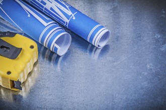 Blue construction drawings measuring tape on metallic background maintenance concept