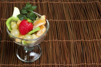 Fruit salad in a glass bowl on wooden base