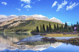 Canada. Rocky Mountains. Sun and mountains are reflected in the smooth water of the lake. Glacial