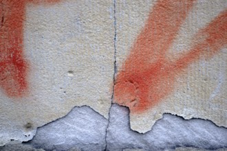 Close-up of a wall with a chipped and painted layer of plaster