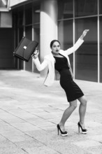 Scared young businesswoman with briefcase and gesturing fear on city background