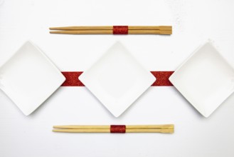 Ceramic bowls and bamboo chopsticks for sushi food with red and white decoration