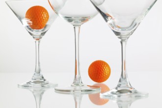 Three glasses of champagne and golf equipments on the glass table