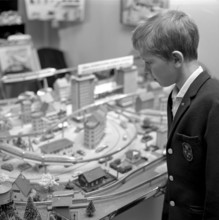 Toys in the 1960s. A boy at a model railway in a store. It's built with buildings and trees and was