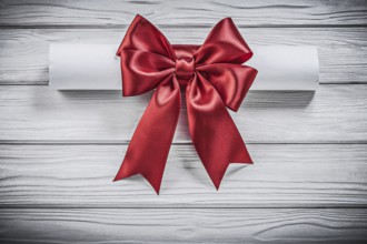 Paper scroll with red bow on wood board holidays concept
