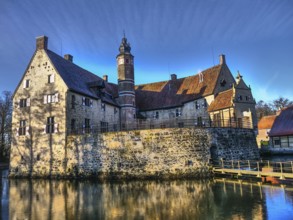 Medieval castle with a moat, shining in the sunlight against a blue sky, Lüdinghausen, münsterland,