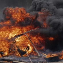 Burning cars tires, strong flame of red-orange fire and clouds of black smoke in sky. Selective