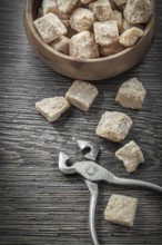 Brown sugar cubes pliers bowl on vintage wood board