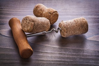 Classical corkscrew and corks of champagne on vintage wooden board alcohol concept