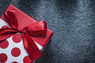 Wrapped gift box with tied bow on black background celebrations concept
