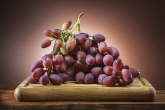 Rose grape on wooden cutting board and brown gradient background