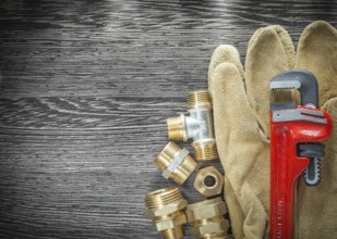 Plumbing pipe wrench fittings safety gloves on wooden board