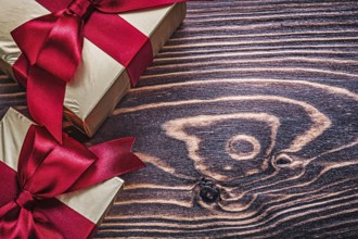 Wrapped gift boxes with red satin ribbons on wood board
