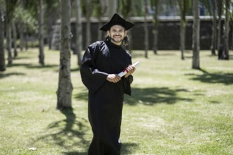 Portrait, student and happy man at graduation with certificate in university campus for success and