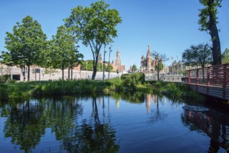 Zaryadye park and Kremlin fortress and St. Basil 's Cathedral in Moscow with pond and reflections,