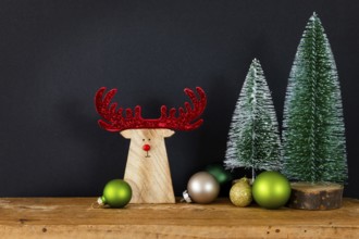 A Christmas decoration black background with tree glass balls and wooden reindeer