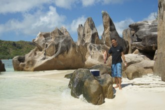Seychelles island Curieuse with the famous granite rocks and man with caught fish