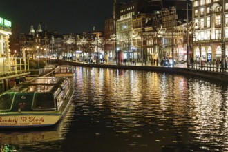 A night view of the canal with illuminated buildings and boats reflected in the water, Amsterdam,