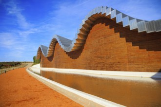 Wave-shaped winery roof. Fragment of the facade is reflected in the pool. Winery - bodega Bodegas