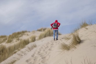 Hiker walking up a sand dune at the beach on a sunny day