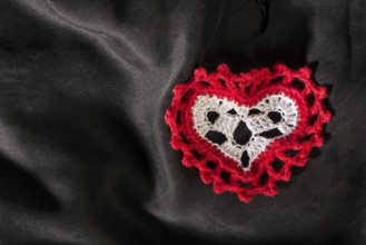 Heart shape made of red textile on black satin
