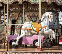 Children's vintage amusement park. White horses on children's carousel