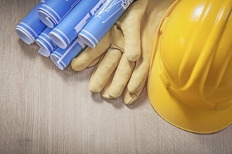 Blue engineering drawings building helmet leather protective gloves on wood board
