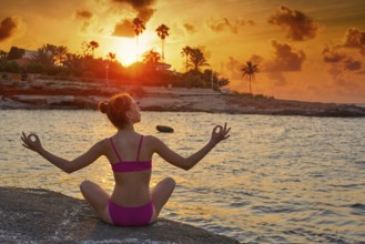 Girl silhouette at beach sunset open arms yoga mudras fingers relaxed sitting