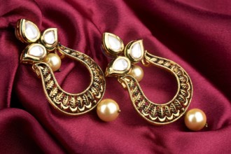Beautiful Golden pair of earrings Diamonds gemstones on a red satin background. Luxury female