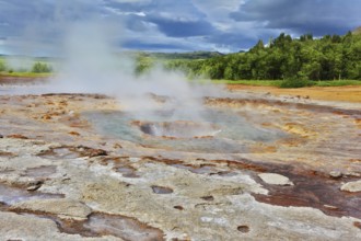 Fumaroles Geyser Strokkur. Water vapor from the crater geyser under bizarre clouds. Summer Iceland