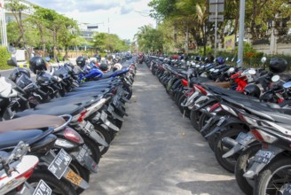:Motorcycles lined up along the busy street in Kuta, Bali