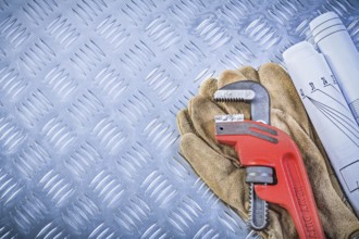 Monkey wrench blueprints leather protective gloves on grooved metal background construction concept