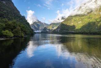 A new morning dawning at Doutful Sound, clouds hanging low in the mountains, South Island of New