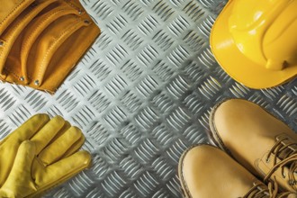 Safety gloves boots building helmet toolbelt on fluted metal texture
