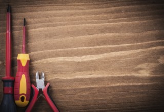 Sharp nippers insulated screwdrivers on wooden board copyspace electricity concept
