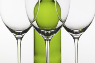 Three empty glasses of wine and green bottle on the white background