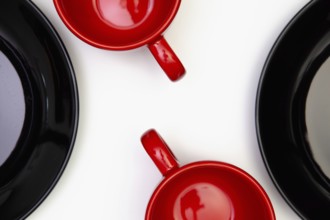 Black plates and red cups on the white table.Top view. Flat Lay Image
