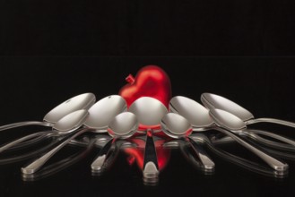 Nine spoons and red heart on a black glass desk